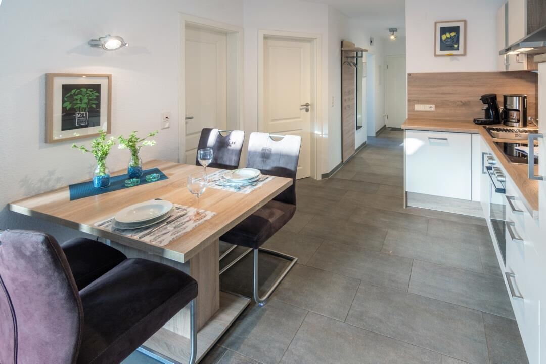 A modern kitchen with white cabinets, a wooden countertop, and a built-in stove.