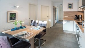 A modern kitchen with white cabinets, a wooden countertop, and a built-in stove. - Ferienwohnung Kleine Auszeit (Norddeich)