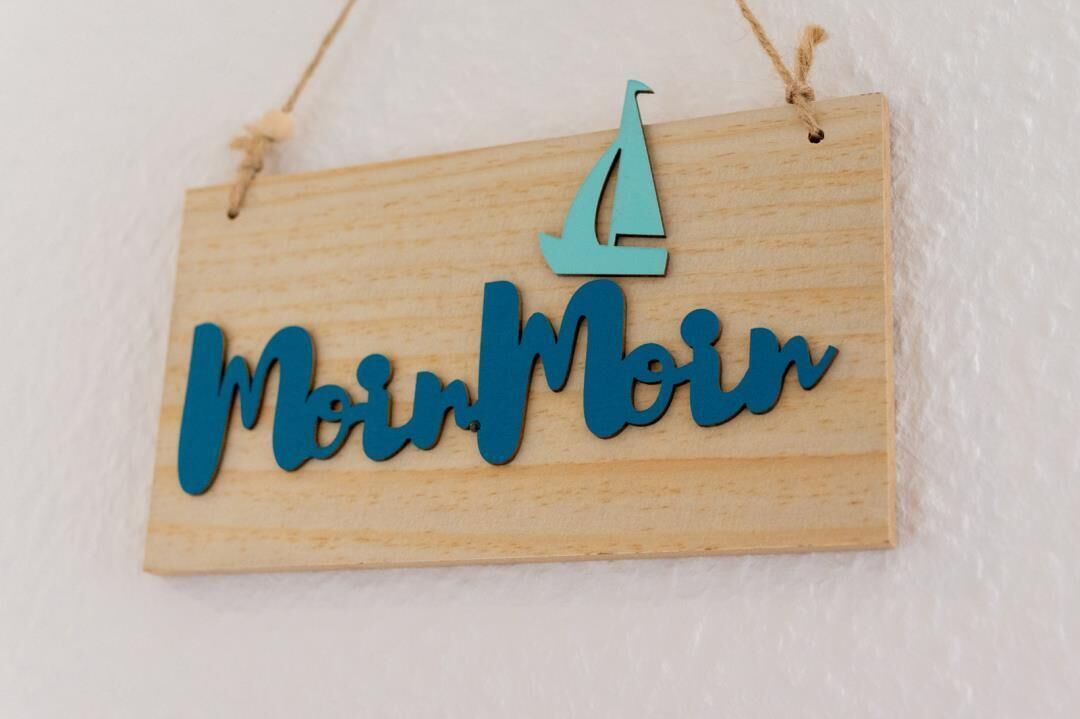 Ein hölzernes Schild mit dem Schriftzug 'MoinMoin' und einem Segelbootsymbol.