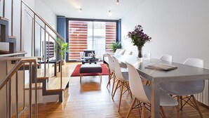 A modern dining area with a long table, white chairs, and a red rug. - My Space Barcelona Park Putxet Rentals (Barcelona)