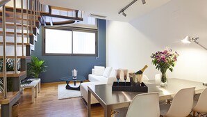 A modern living space with a dining area, a staircase, and a large window providing natural light. - My Space Barcelona Park Putxet Rentals (Barcelona)