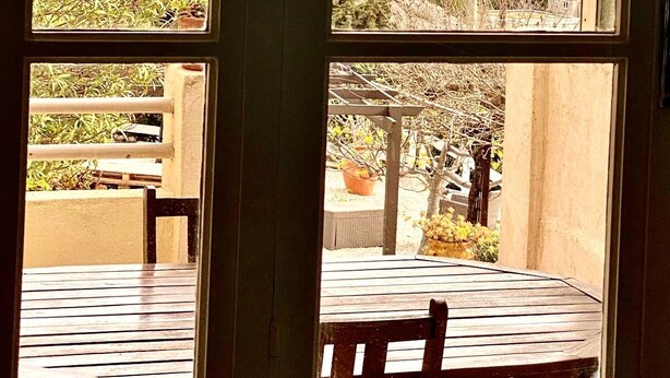 A room with a view of a body of water, mountains, and a tree outside the window. - Appartement Laura. Terrasse, vue mer (Le Rove)