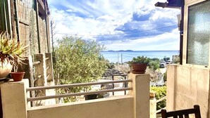A balcony with a view of the sea, a wooden table, and potted plants. - Appartement Laura. Terrasse, vue mer (Le Rove)