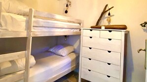 A small, cozy room with a bunk bed, a white dresser with drawers, and a decorative light fixture. - Appartement Laura. Terrasse, vue mer (Le Rove)