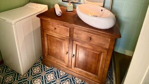 Une salle de bain avec un meuble-lavabo en bois, un lavabo blanc, un miroir et un lave-linge.