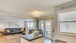 Un salón amplio con sofá, mesa de centro y comedor con mesa y sillas. Se observa también una zona de cocina con encimera y armarios.
