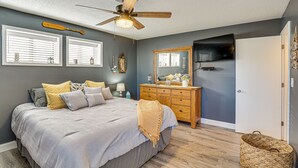Un dormitorio con cama, cómoda de madera y ventilador de techo.