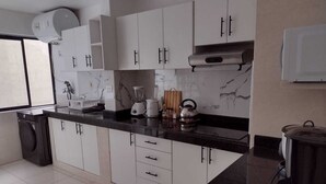 A modern kitchen with white cabinets, a black countertop, and a stainless steel range hood.