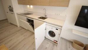 Eine kompakte Küche mit integriertem Wasch- und Trockner, Spüle und Mikrowelle.