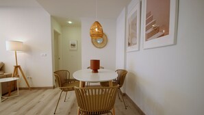 Ein Essbereich mit einem runden Tisch, vier Stühlen, einer Lampe und einem gerahmten Bild an der Wand.