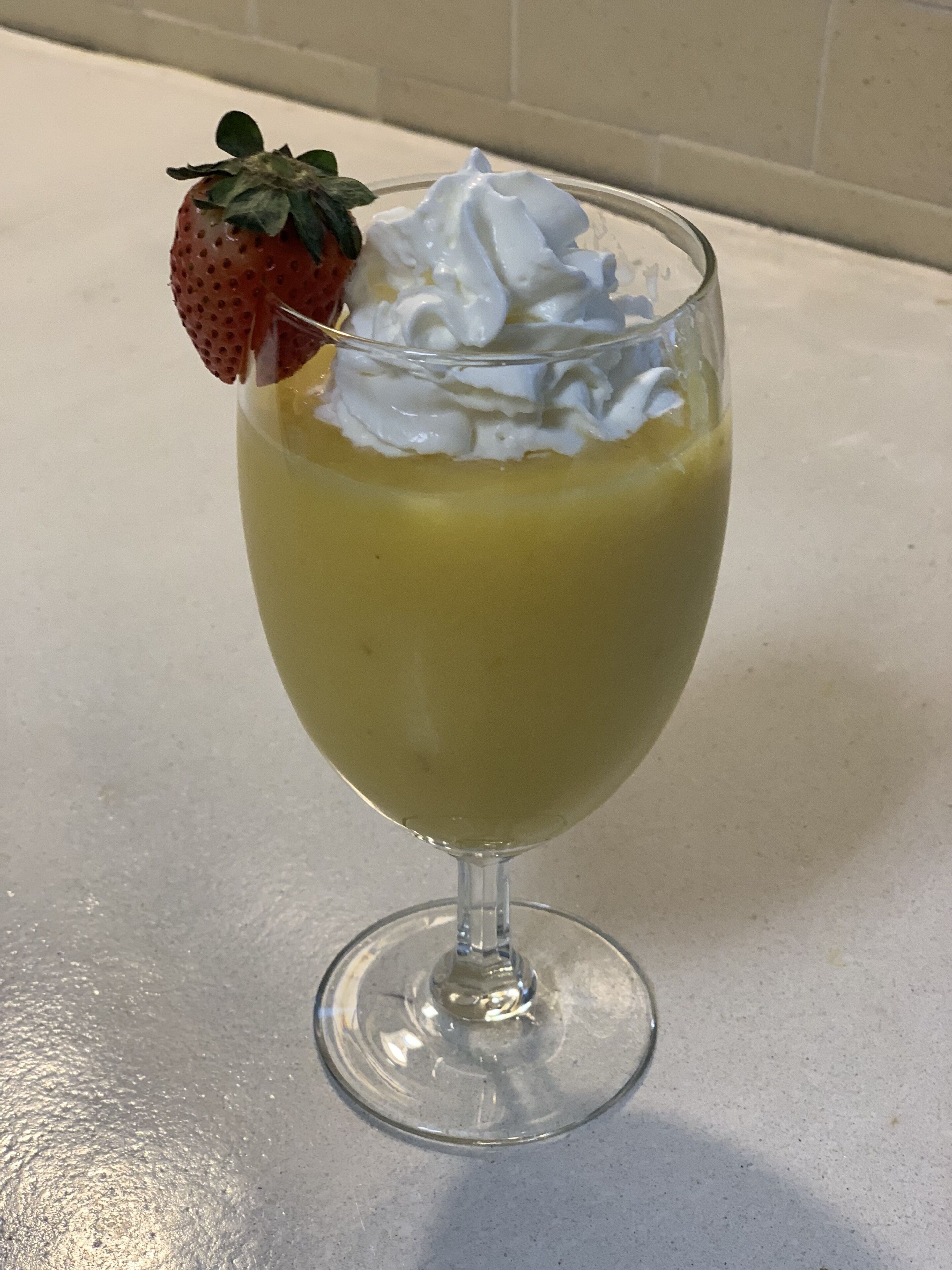 A dessert in a clear glass with a strawberry on top.