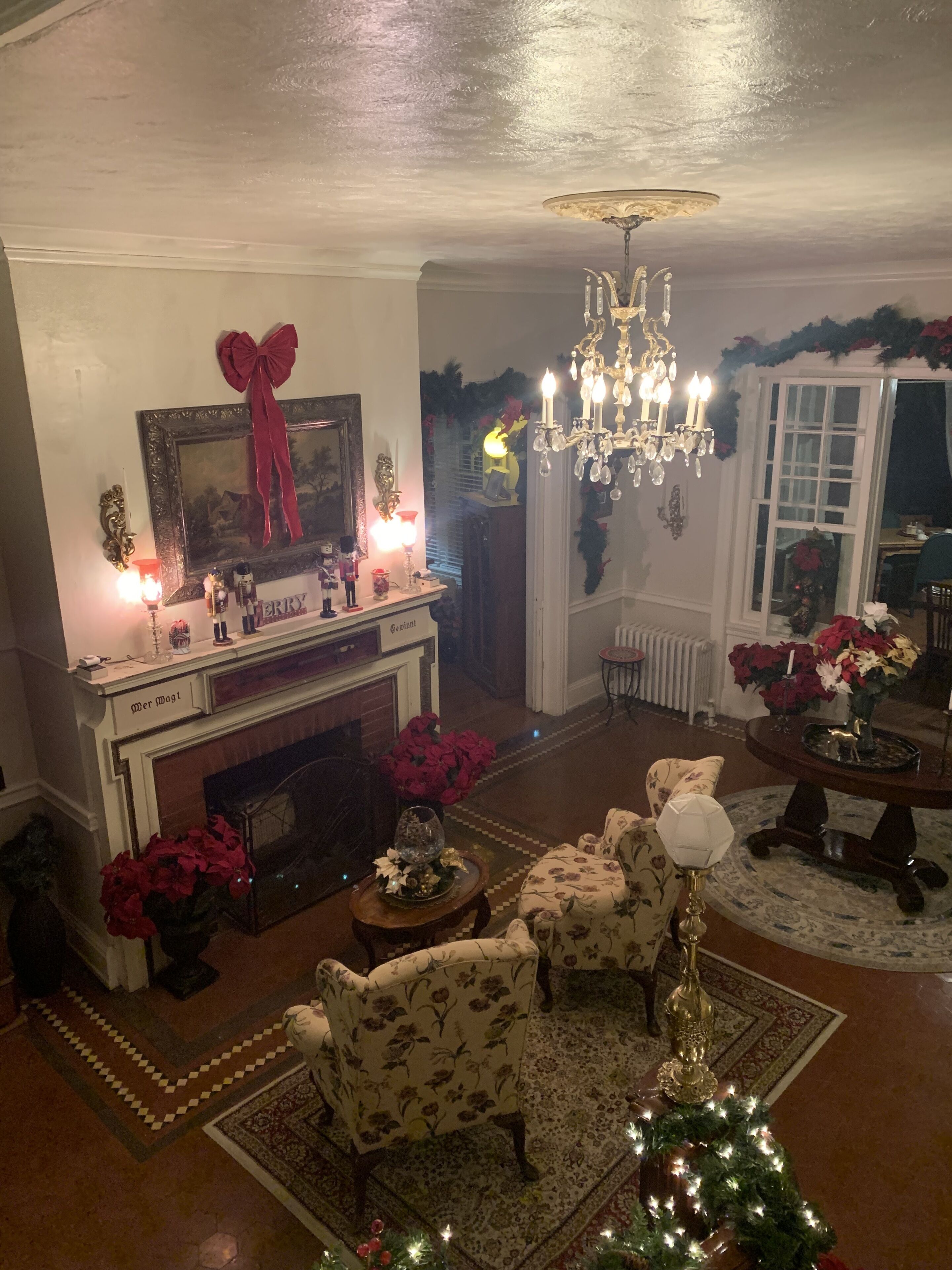 A cozy living room with a fireplace, floral armchairs, and festive decorations.