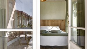 Quarto com cabeceira de madeira, cama com roupa de cama branca e janela com cortinas.