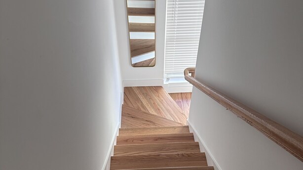 Una escalera de madera con paredes blancas y barandilla de madera.
