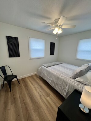A bedroom with a bed, a chair, a nightstand, and a ceiling fan. - Stylish In-Town Retreat - 2 Bedroom, 1 Bathroom - Modern Comfort (Marion)
