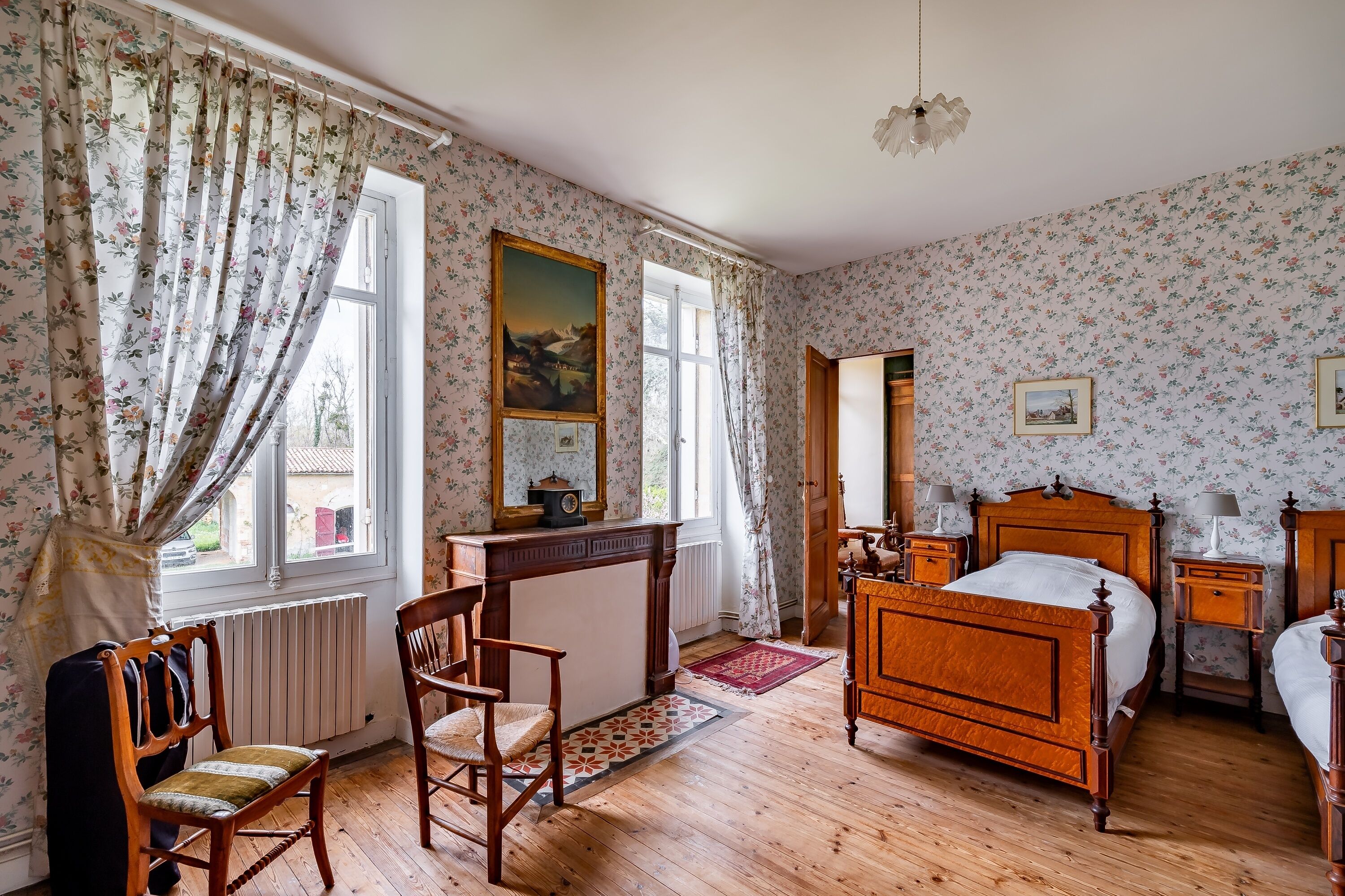Ett sovrum med en säng i trä, ett skrivbord, en stol och ett element.