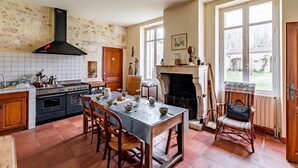 Una cocina amplia con una isla grande, una chimenea y vistas al jardín a través de las ventanas.