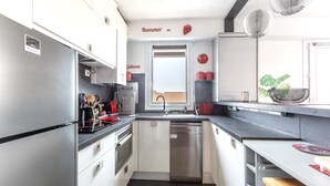 Een moderne keuken met roestvrijstalen apparatuur, witte kastjes en uitzicht op buiten.