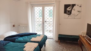 A bedroom with two beds, a bench, a TV, and a window with a view. - Sunnyhome- Ostia Lido sea view | 2 bathrooms (Lido di Ostia)