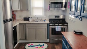 Una cocina con un refrigerador de acero inoxidable, un microondas, una estufa y un lavamanos.