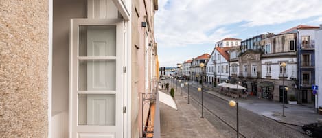 A narrow street with buildings on either side, a cobblestone path, and a few outdoor seating areas.