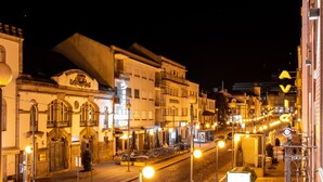 Vista nocturna de una calle con edificios, farolas y un paso de peatones.