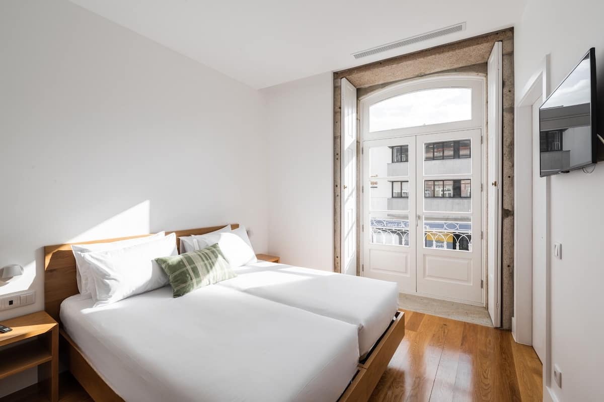 Habitación de hotel con cama, mesita de noche y televisor montado en la pared.