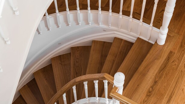 Una escalera de caracol con balaustres blancos y escalones de madera.
