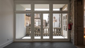 Una habitación con un amplio ventanal corredero que da a un balcón con barandilla de hierro forjado.