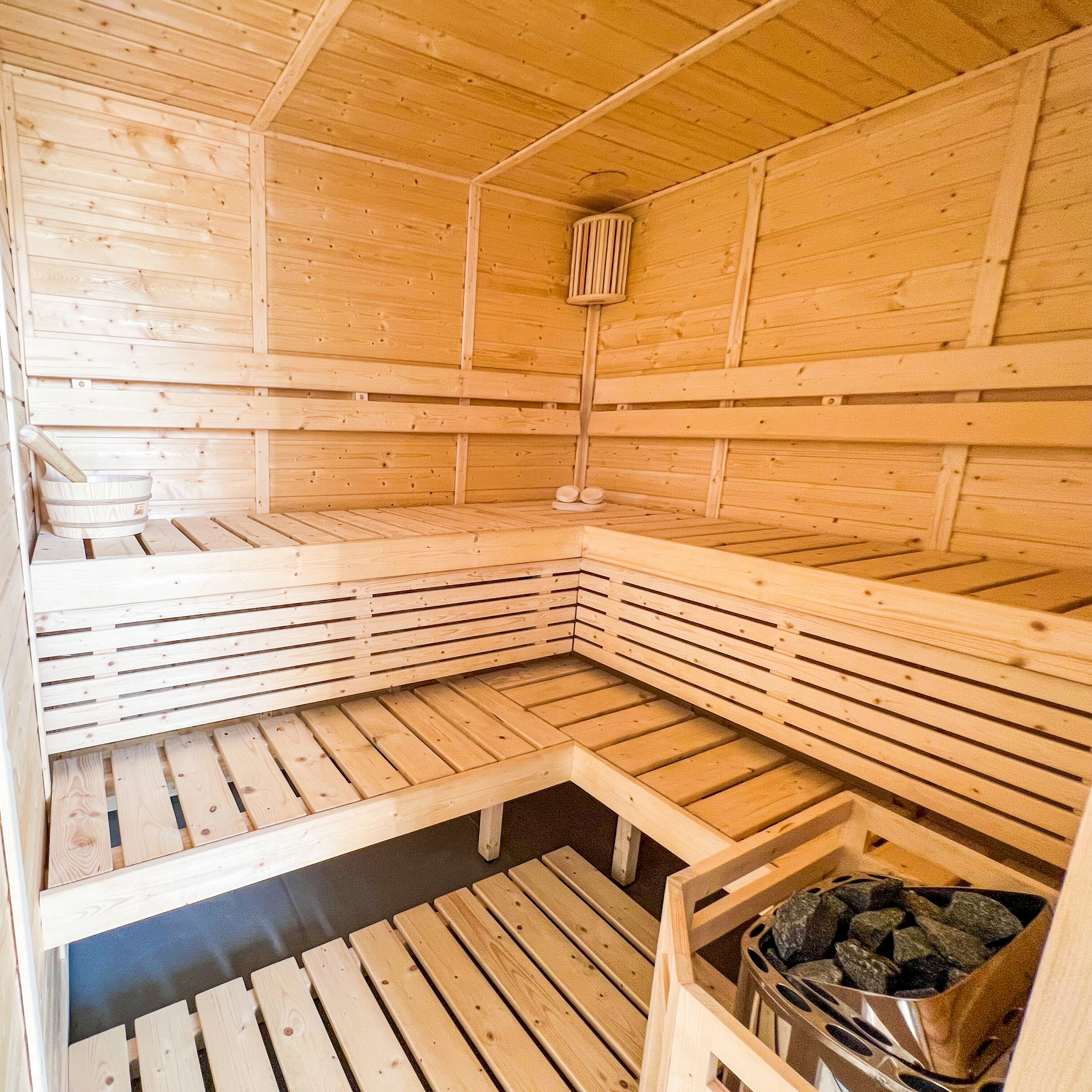 A sauna with wooden benches and a stone basin.
