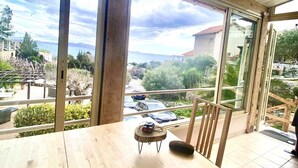Habitación amplia con una gran mesa de madera, una silla y vistas a una zona residencial a través de amplios ventanales.