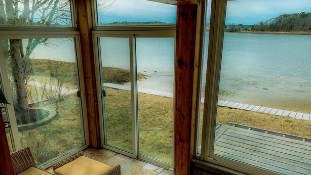 Una habitación con un amplio ventanal corredera que da a una terraza con vista al agua.