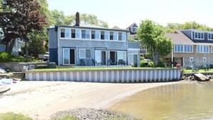 Una casa de dos plantas con un patio y un muelle que se adentra en un lago.