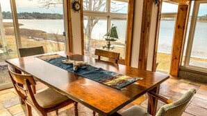 Una mesa de comedor de madera con sillas, un tapete y una pequeña decoración de un velero.
