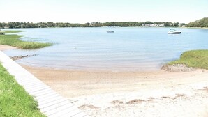 Un lago tranquilo con una playa arenosa y un paseo marítimo de madera.