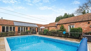 A swimming pool with a tiled deck, surrounded by a brick building with a tiled roof and a fenced patio area. - 5 bedroom accommodation in Thorpe Culvert, near Skegness (Thorpe Culvert, near Skegness)