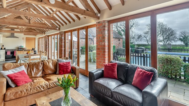 A spacious living area with a high ceiling, wooden beams, a large window, and a view of the outside. - 5 bedroom accommodation in Thorpe Culvert, near Skegness (Thorpe Culvert, near Skegness)