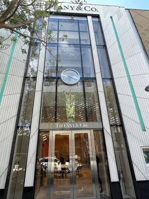 A modern building with a large glass facade, a visible clock, and the name 'TIFFANY & CO.' on the entrance. - In the heart of the Miami Design District (Miami)