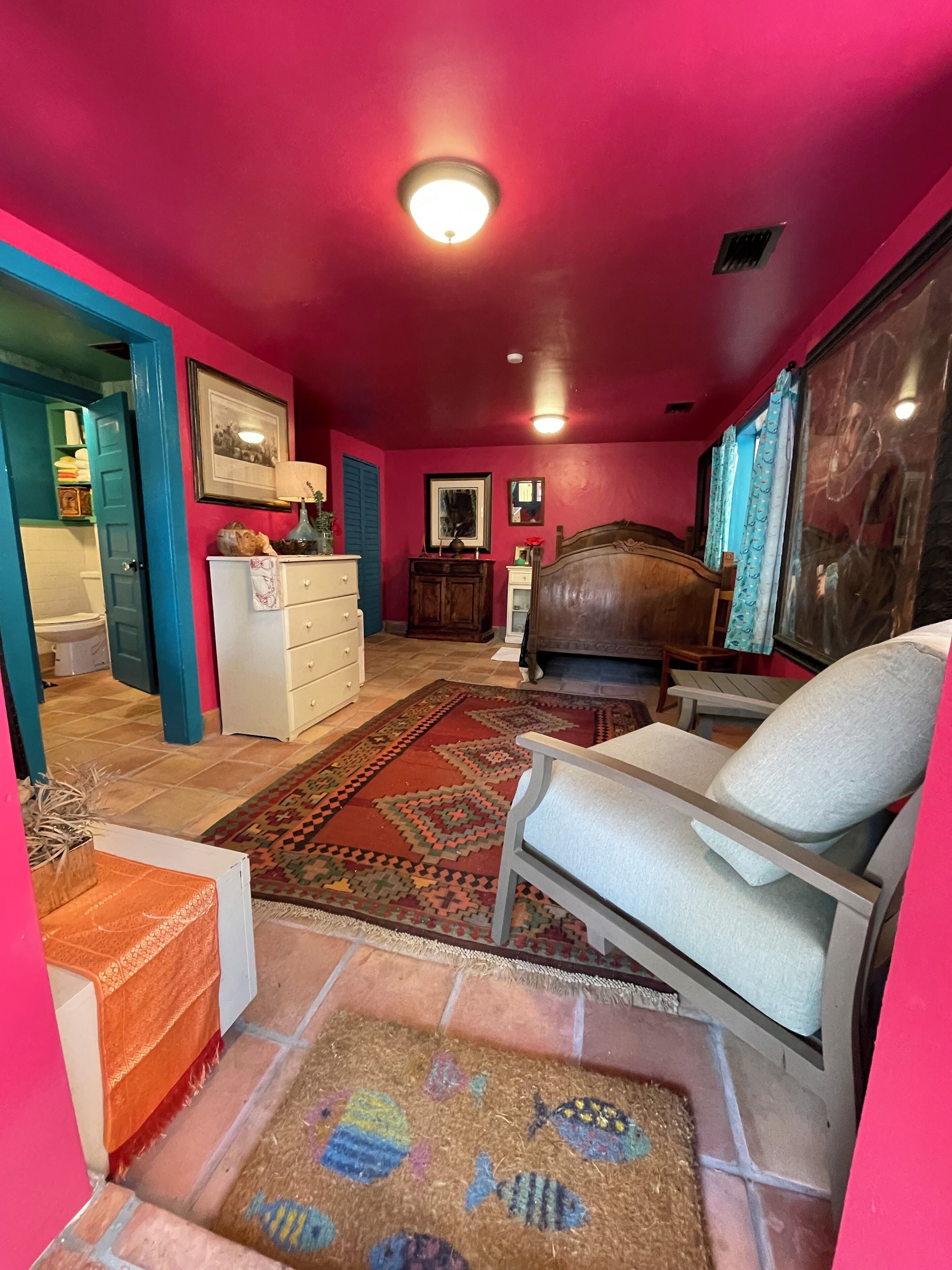 A room with a bed, a chair, a dresser, and a rug.