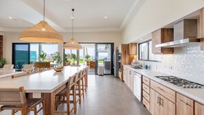 Una cocina moderna con armarios de madera, una isla grande, luces colgantes y vistas al exterior.