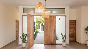 Un interior moderno con una puerta de madera, plantas en macetas y una lámpara colgante.