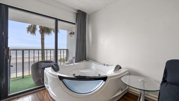 A modern bathroom with a large bathtub, a glass table, and a view of the beach. - Bello condominio con vista al mar, jacuzzi interno y una ubicación privilegiada (Galveston)