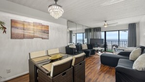 A spacious living area with a dining table, sofas, a TV, and a balcony with a view of the sea. - Bello condominio con vista al mar, jacuzzi interno y una ubicación privilegiada (Galveston)