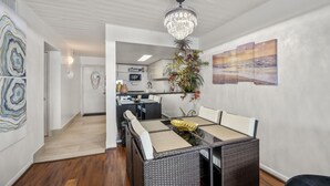 A modern dining area with a glass-top table, wicker chairs, and a chandelier. - Bello condominio con vista al mar, jacuzzi interno y una ubicación privilegiada (Galveston)