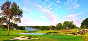 A golf course with a water hazard, sand bunkers, and a flagstick.