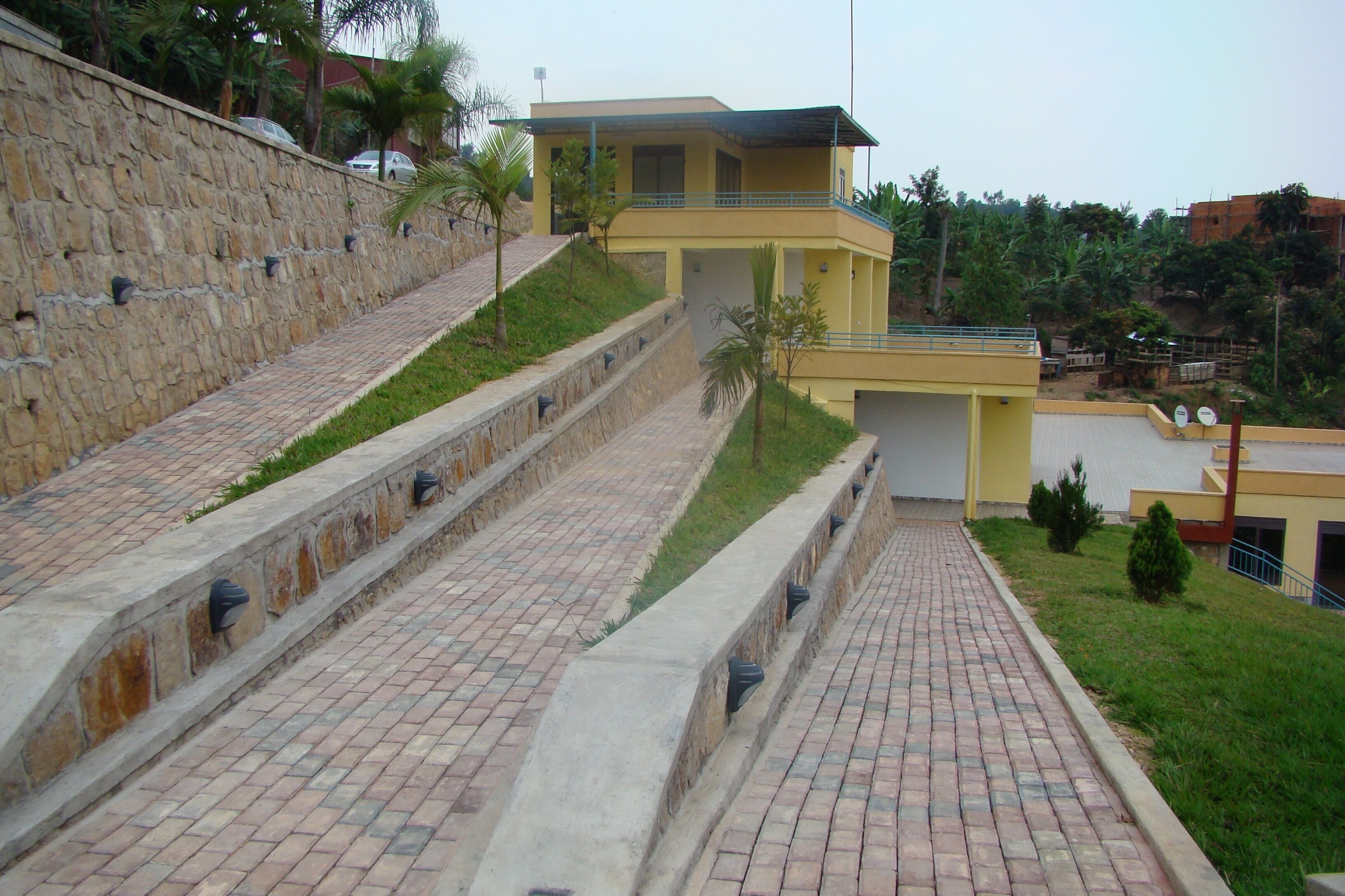 A multi-level building with a stone retaining wall and a paved pathway.