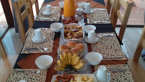 A table set for breakfast with various dishes, including fruits, pastries, and a coffee pot. - Palega Beach Inn (Boneza)