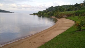 A beach with a grassy area and a house in the background. - Palega Beach Inn (Boneza)