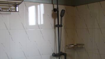 A bathroom with a white sink, a shower with a handheld showerhead, and a towel rack.
