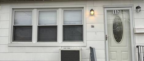 A two-story house with a white exterior, a front door with a glass panel, and a small porch with steps.